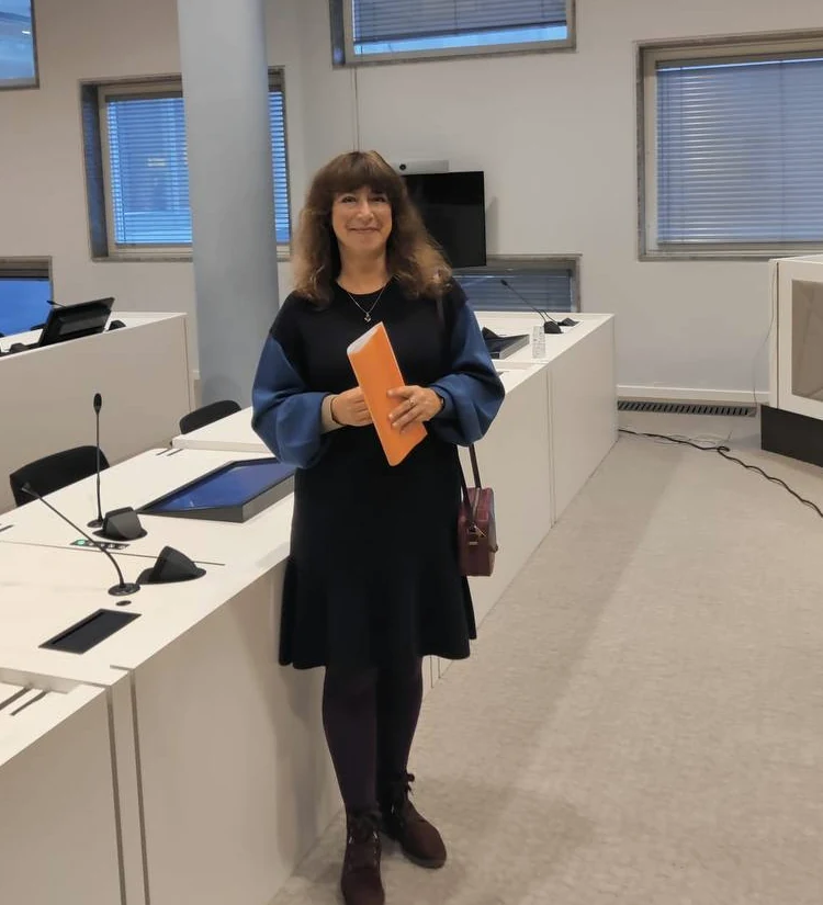 Iana Solonina met een oranje map in een vergaderruimte